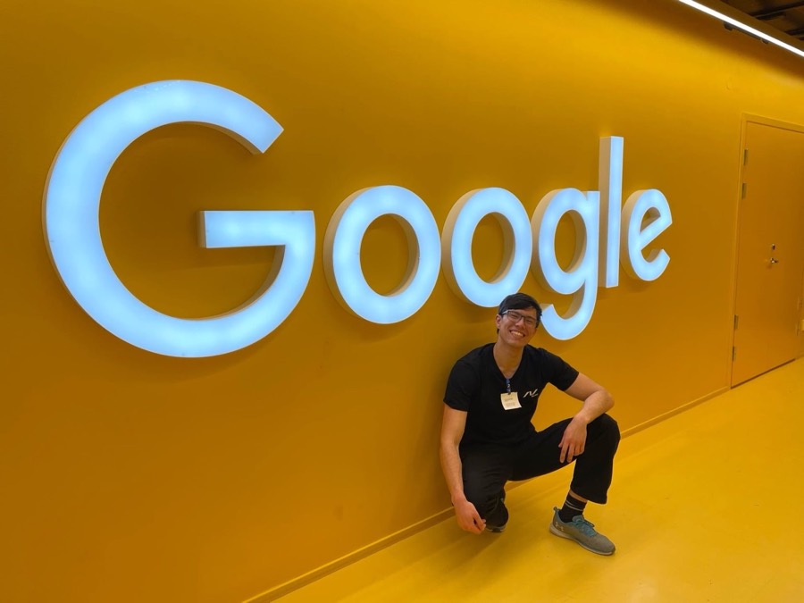 Jonas Hulthén crouching under the illuminated Google logo at the Google Stockholm office