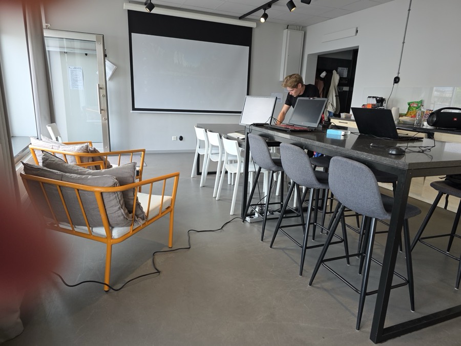 Bright workspace with laptops on a high table and a projector screen